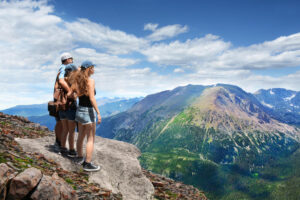 Father with arms around his family looking at summer mountains