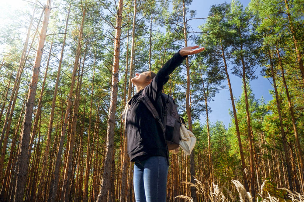 smiling happy woman hiking in forest with outstretched hands