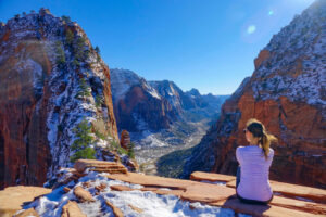 Traveler girl sits and observes the snowy canyon
