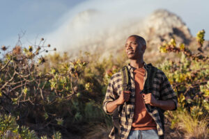 Young man wearing a backpack standing on a trail