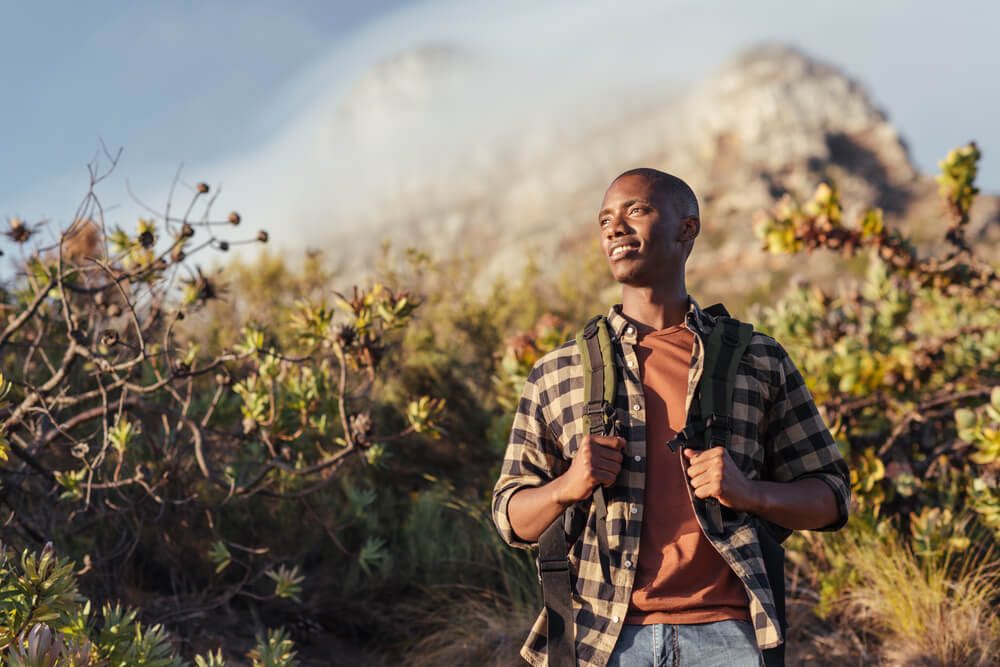 Young man wearing a backpack standing on a trail