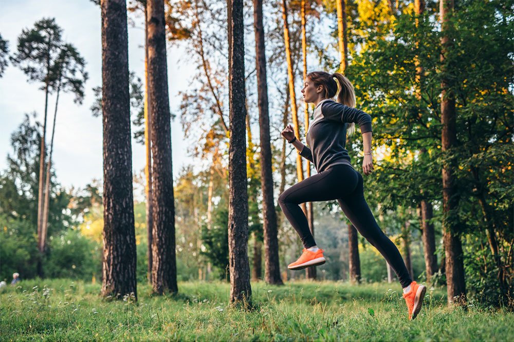 Young female athlete jogging in forest